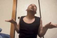 a man in a black tank top is making a funny face with his hands in the air .