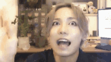 a man is making a funny face while sitting at a desk in front of a computer .
