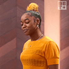 a woman wearing a yellow shirt and earrings is smiling