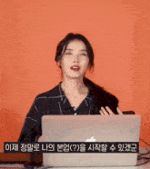 a woman sitting in front of a laptop with korean writing on the bottom