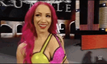 a woman with pink hair is smiling in front of a sign that says ' wwe ' on it