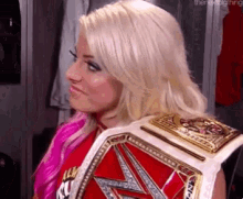 a woman is holding a wrestling championship belt on her shoulder .