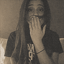 a woman is covering her mouth with her hands and wearing a shirt that says am 9