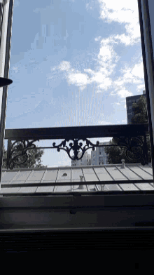looking out a window at a building with a blue sky and clouds