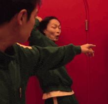 a man and a woman are standing next to each other in front of a red door