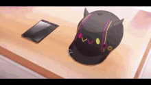 a black hat with horns is sitting on a table next to a cell phone