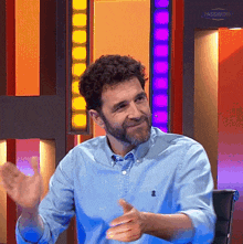 a man with a beard wearing a blue shirt is clapping his hands in front of a sign that says password