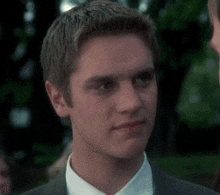 a young man in a suit and white shirt is looking at another man