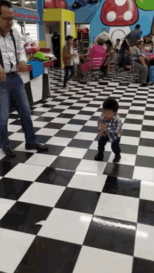 a little boy is walking on a checkered floor in a store