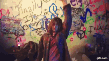 a person standing in front of a wall with graffiti on it including the word finally