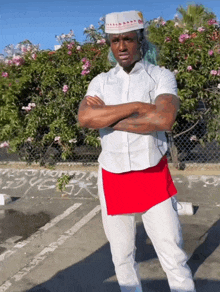 a man standing in a parking lot with his arms crossed and a hat that says ' in n out ' on it