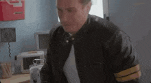 a man in a leather jacket is standing in a room with a medical device .