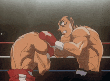 two men are boxing in a ring and one is wearing red boxing gloves