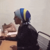 a woman wearing a striped head scarf is sitting at a table