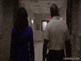 a man and a woman are walking down a hallway with gifrun.com written on the bottom of the screen