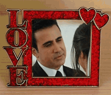 a picture frame with the word love on it and a man and woman looking at each other