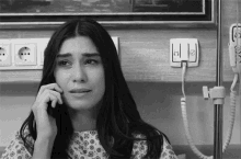 a woman in a hospital gown is crying while talking on a cell phone .