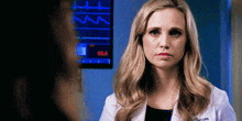a woman in a lab coat is looking at another woman in front of a monitor that says 98.4