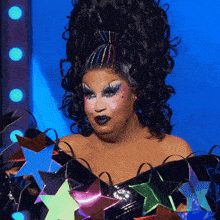 a drag queen is wearing a black top with a bunch of stars on it