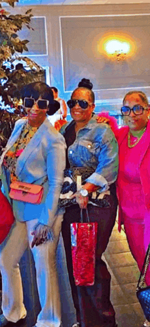 three women are posing for a picture together and one of them is wearing a pink outfit .
