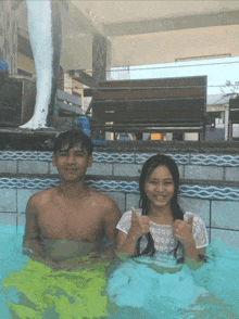 a man and a woman are in a swimming pool and the woman is giving a thumbs up