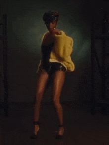a woman wrapped in a yellow towel is dancing in a dark room