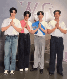 a group of young men standing next to each other with their hands folded in front of a wall that has the letter u on it