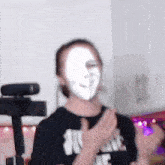 a person with a white mask on their face is standing in front of a webcam .