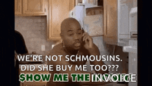 a man is talking on a cell phone in a kitchen while sitting at a table .