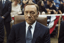 a man in a suit and tie sits in a chair