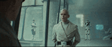 a woman in a trench coat stands in front of storm trooper soldiers