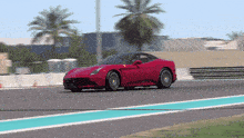 a red sports car is driving down a road with palm trees in the background