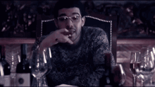a group of people are sitting around a table with wine bottles
