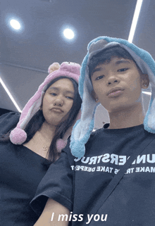 a boy and a girl are posing for a picture and the girl is wearing a hat that says i miss you