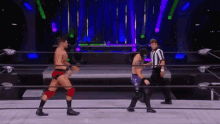 two men are wrestling in a wrestling ring while a referee looks on .