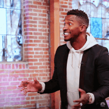 a man in a suit is standing in front of a brick wall with the words world of dance on the bottom