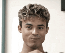 a young man with curly hair is making a face