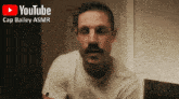 a man with a mustache is sitting in front of a youtube logo