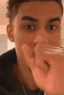 a young man is covering his mouth with his hand while making a funny face .