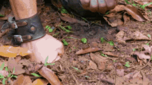 a person wearing a leather wristband is standing on a pile of dirt .