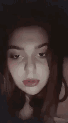 a close up of a woman 's face in a dark room with a shadow on her face .