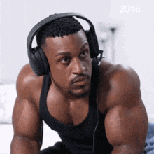 a man wearing headphones and a black tank top with the year 2018