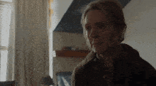 a close up of a woman 's face in a room with a window .