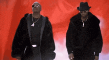 two men are standing next to each other wearing black jackets