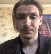 a man with long hair and a beard is wearing a black shirt