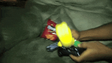 a person is holding a yellow object in front of a bag of potato chips