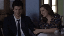 a man in a suit and tie sitting next to a woman who is smiling