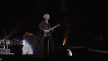 a man playing a guitar on a stage with the letter d in the upper right corner