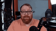 a man with glasses and a beard is talking into a microphone in front of a chair that says secret lab