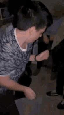 a young boy is dancing in a room while a group of people watch .